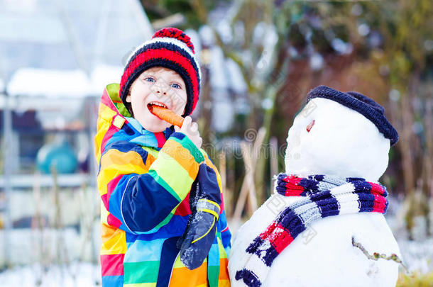 有趣的男孩穿着五颜六色的衣服在<strong>户外堆雪人</strong>