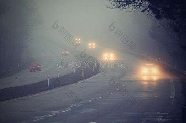 雾中的汽车。 恶劣的冬季天气和道路上危险的汽车交通。 雾中的轻型车辆。