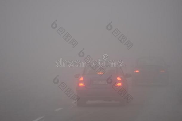 雾中的汽车。 恶劣的冬季天气和道路上危险的汽车交通。 雾中的轻型车辆。
