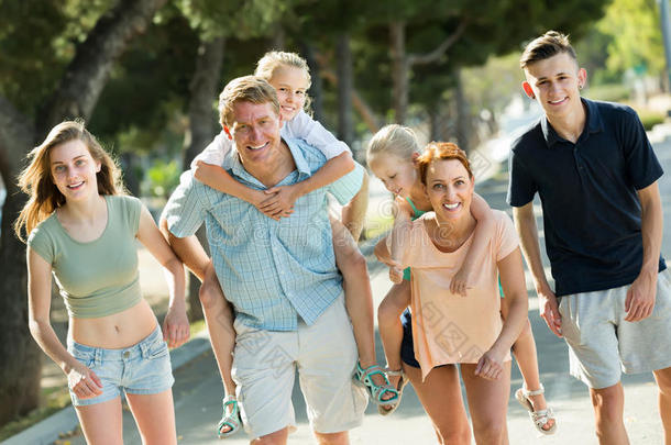 一个由六个人组成的大家庭，带着孩子在夏天的城市里和父母一起散步