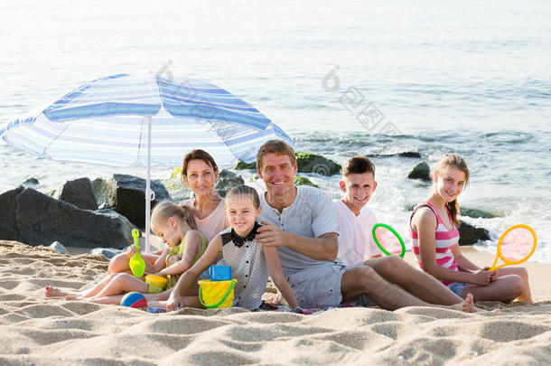 活跃的家庭和孩子一起坐在海滩上