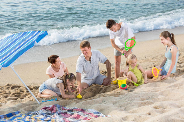 无忧无虑的六个人家庭在海滩上一起玩