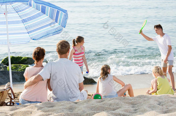 家庭有四个孩子在海滩上放松