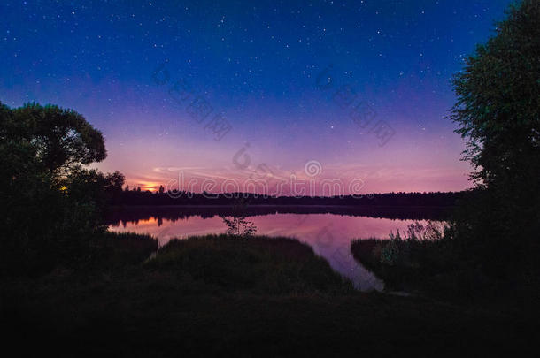 森林湖畔的美丽夜景，春天星光灿烂，水中云彩倒映。多姿多彩的天空。自然背景