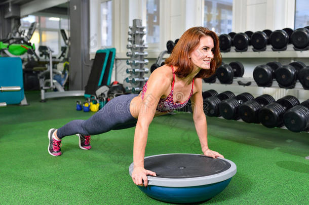 健身妇女计划做体重运动的核心力量训练在健身房与博苏平衡教练