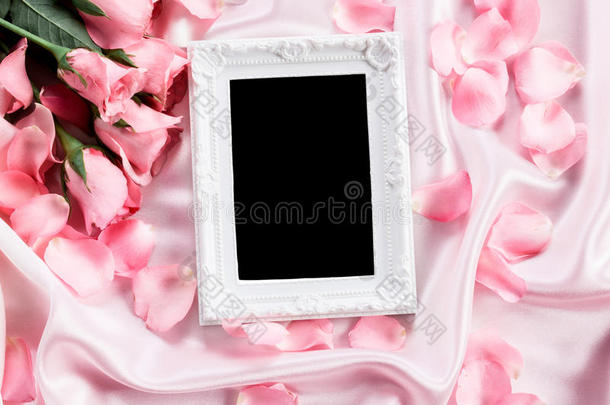 空相框，在柔软的粉红色丝绸织物上有一束甜美的粉红色玫瑰花瓣