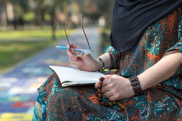 阿拉伯学生坐在大学公园里做手工笔记
