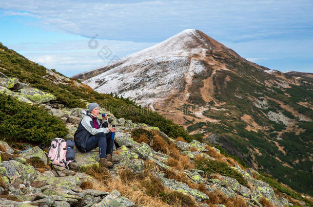 女徒步旅行者坐在青石上俯瞰风景秀丽的山景