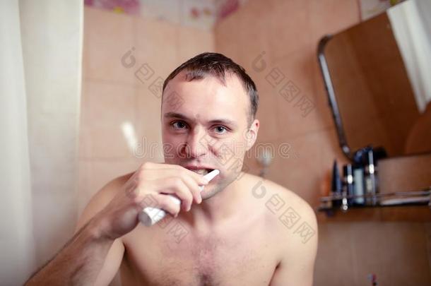 特写肖像男子在浴室刷牙，电刷和鬼脸扮演傻瓜
