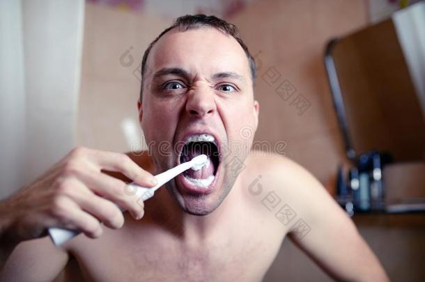 特写肖像男子在浴室刷牙，电刷和鬼脸扮演傻瓜