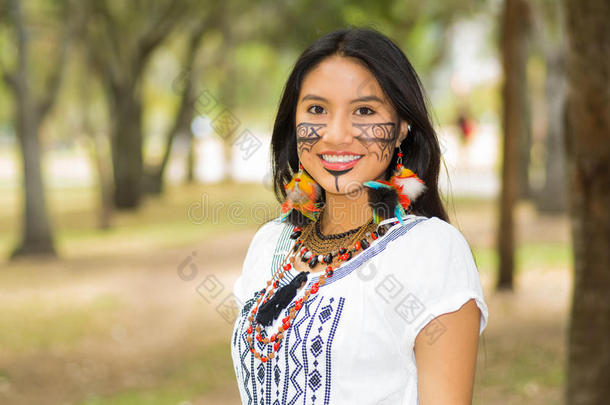 美丽的亚马逊河女人，脸上涂着当地人的颜料，穿着白色的传统服装，在公园里愉快地摆姿势拍照