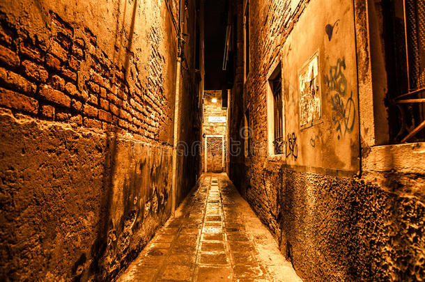 古老狭窄的街道和古中世纪建筑的立面在夜间特写。 威尼斯，意大利