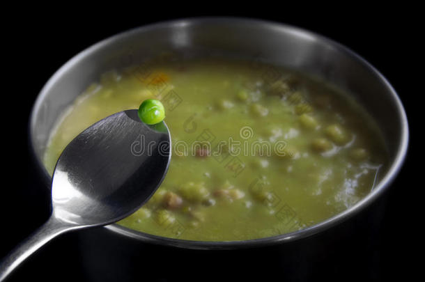 新鲜的青豌豆在一个勺子上，放在一个锅里，里面有<strong>煮</strong>熟的汤