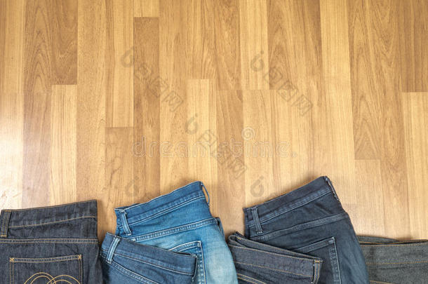 棕色木制背景上的蓝色牛仔裤和蓝色牛仔裤牛仔色