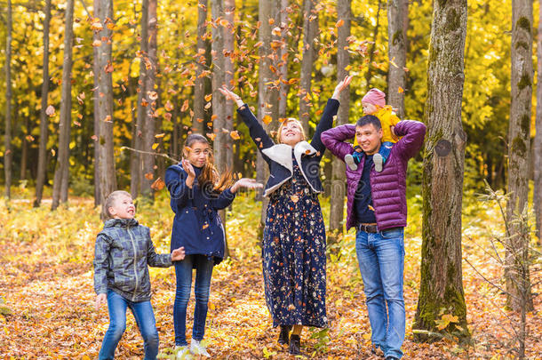 家庭，童年，季节和人的概念-快乐的家庭玩秋天的叶子在公园