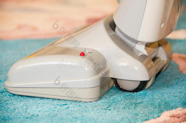关闭一个现代吸尘器的头部，正在使用，同时厚厚的白色地毯
