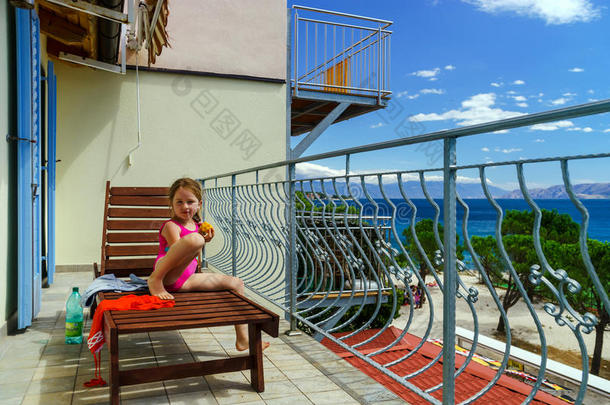可爱的小女孩在海边的阳台上晒太阳