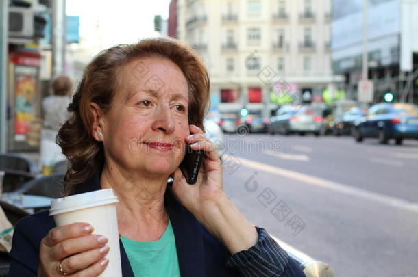 女商人一边用手机走路一边用智能手机说话。快乐微笑的白种女商人忙碌着。巴塞罗那图片