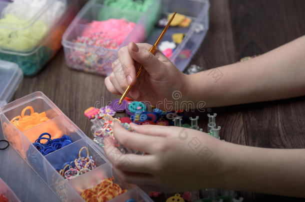 孩子们的手在用彩色橡胶编织图形