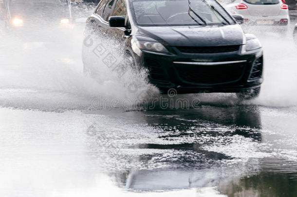 在倾盆大雨中，潮湿的道路上模糊的黑色汽车