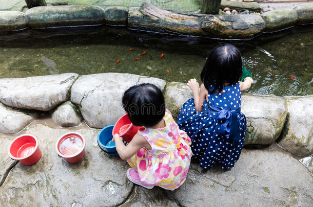 亚洲中国小女孩在池塘用铲子网捕鱼