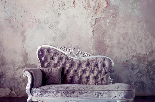 灰色风格的内部。 美丽的沙发在古典风格的背景下纹理墙壁。 紫色的色调