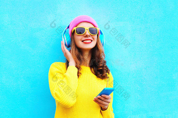 时尚漂亮，无忧无虑，女孩在耳机里听音乐，戴着五颜六色的粉红色<strong>帽子</strong>，戴着<strong>黄色</strong>太阳镜