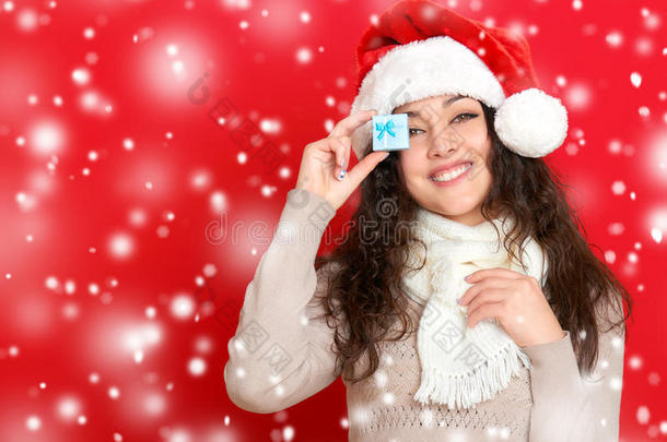 女孩在圣诞帽肖像与小礼品盒摆在红色背景，圣诞节假日概念，快乐和情感