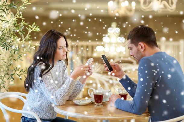 一对夫妇用智能手机在咖啡馆喝茶
