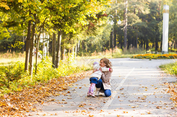 可爱的小女孩和年轻的女人在美丽的秋天森林。 女儿跑到妈妈身边。 家庭肖像，秋天