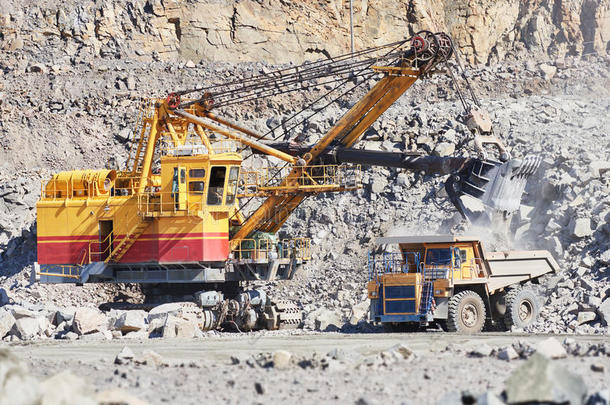 挖掘机在露天将花岗岩或矿石装入自卸车