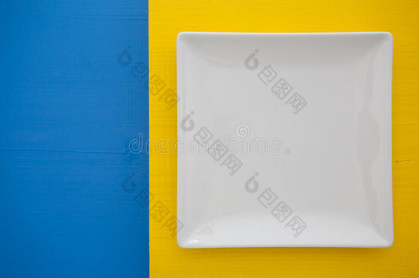 蓝色和黄色背景上的白色陶瓷盘，