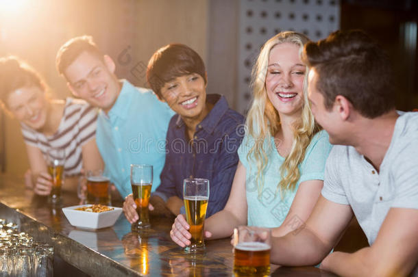一群朋友在酒吧柜台喝啤酒时互相交流