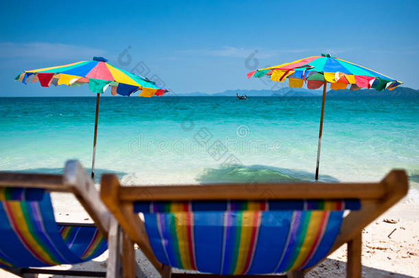 沙滩椅下五颜六色的雨伞在沙滩普吉岛上，