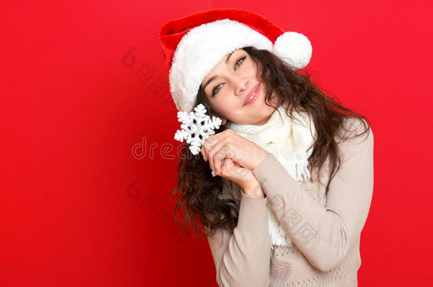 女孩在圣诞帽肖像与大雪花玩具摆在红色背景，圣诞节假期的概念，快乐和情感