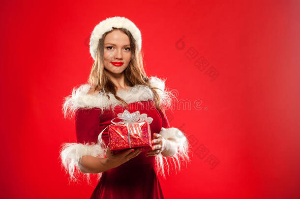 圣诞节，圣诞节，冬天，幸福的概念-微笑的女人戴着圣诞老人的帽子，带着<strong>礼品</strong>盒，<strong>红色背景</strong>