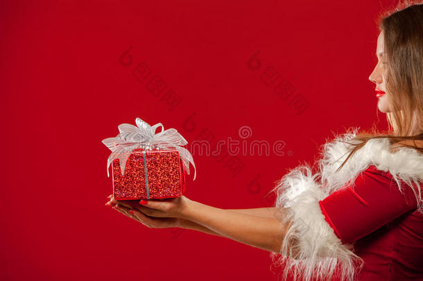 圣诞节，圣诞节，冬天，幸福的概念-微笑的女人戴着圣诞老人的帽子，带着<strong>礼品</strong>盒，<strong>红色背景</strong>。
