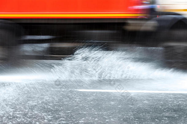 汽车行驶在被洪水淹没的城市道路上，溅起雨水