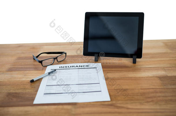 数字平板电脑，保险表格，眼镜和笔在桌子上