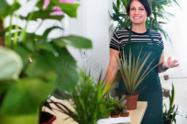 快乐的女人花店在盆栽植物中微笑
