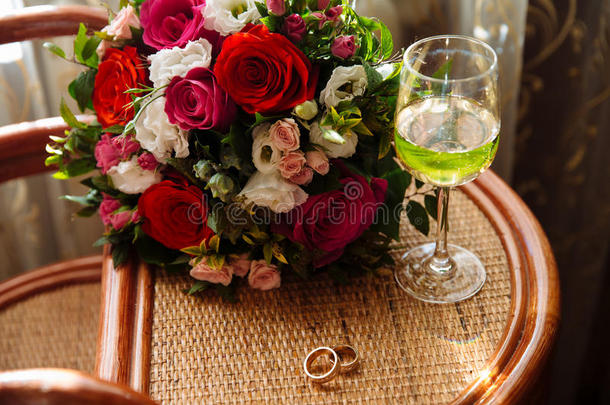 金色的结婚戒指，一杯香槟，桌上的花束