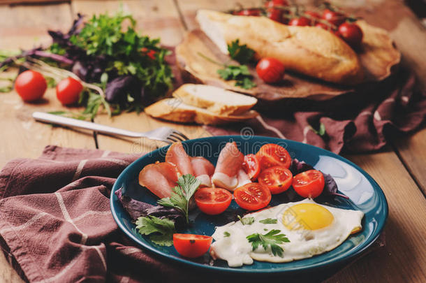 煎鸡蛋配西红柿，罗勒和意大利火腿，桌子为舒适的早餐