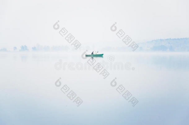 一个秋天的早晨，在湖上<strong>浓</strong>雾</strong>中，船上只有一个渔夫