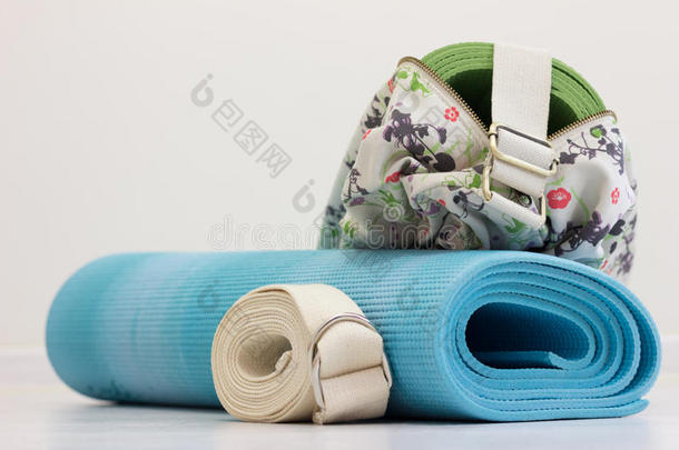 蓝色瑜伽垫，皮带和绿色瑜伽垫在袋子里