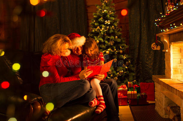 一家人在圣诞节的时候坐在壁炉前的沙发上读故事