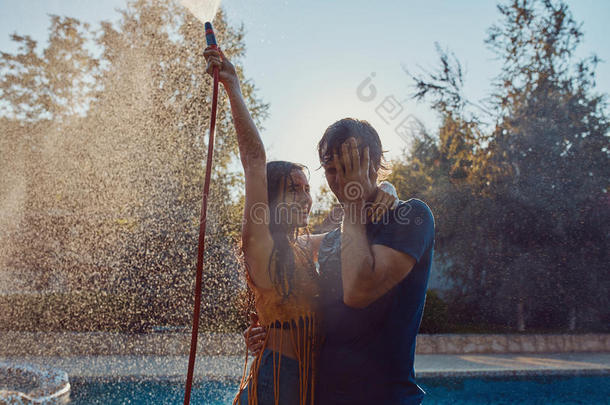 一对有乐趣的夫妇用花园软管互相倒水