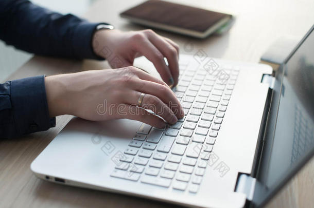 双手在笔记本电脑键盘上打字。 男人在他的工作场所的办公室工作
