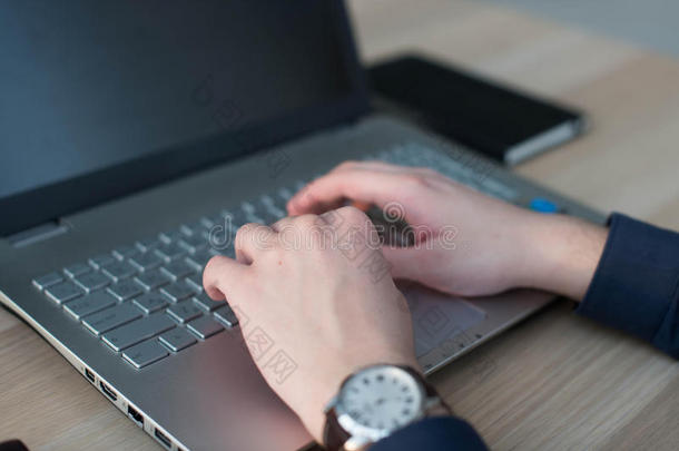 双手在笔记本电脑键盘上打字。 一个人在他的工作场所的办公室工作