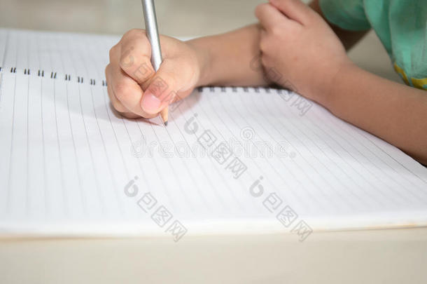 儿童手在空白笔记本铅笔上写字，并在v中复制空格