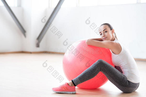 漂亮的执着的女人坐在健身球附近